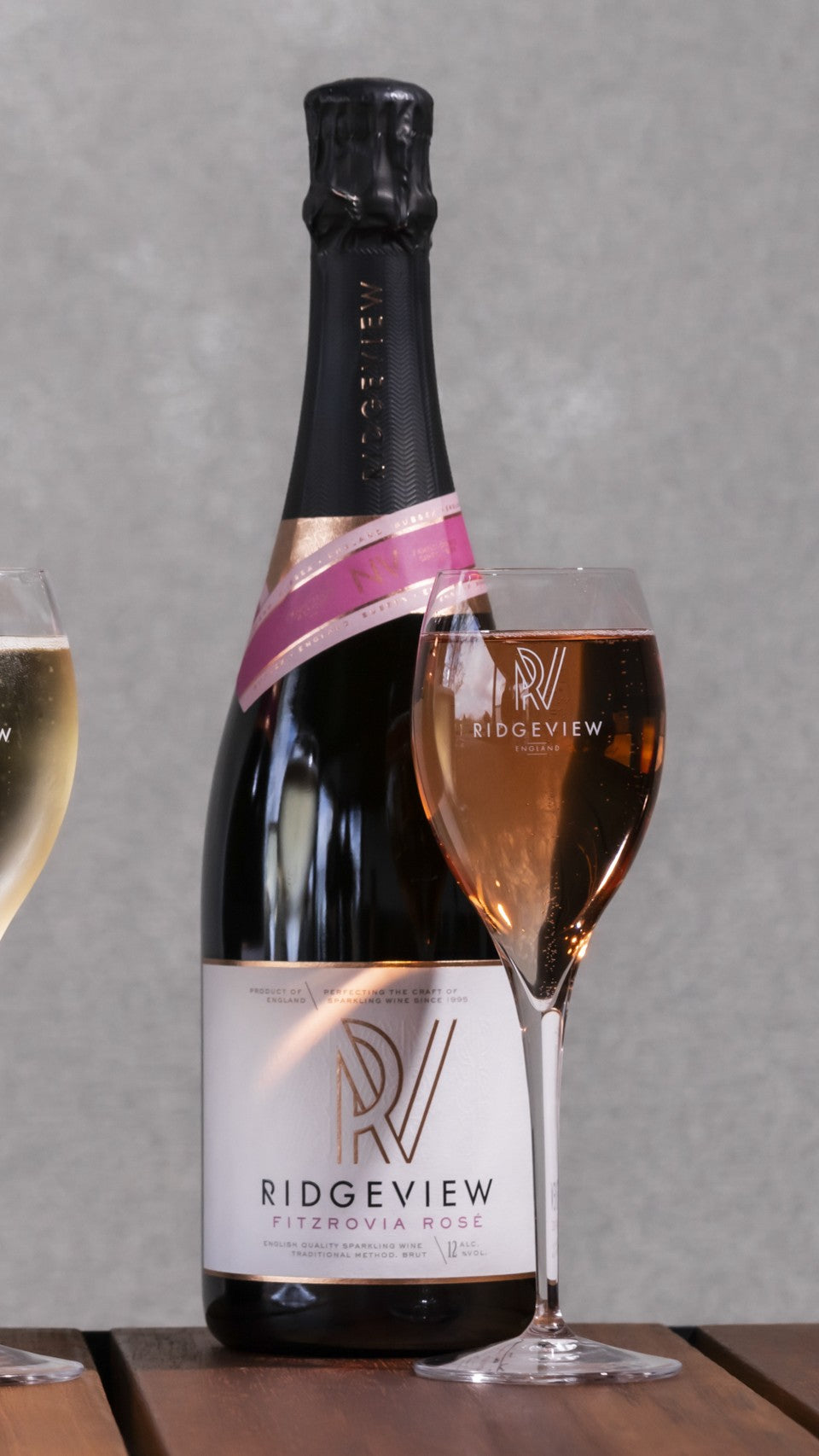 Bottle of Ridgeview Fitzrovia Rosé sparkling wine with a glass on a wooden surface