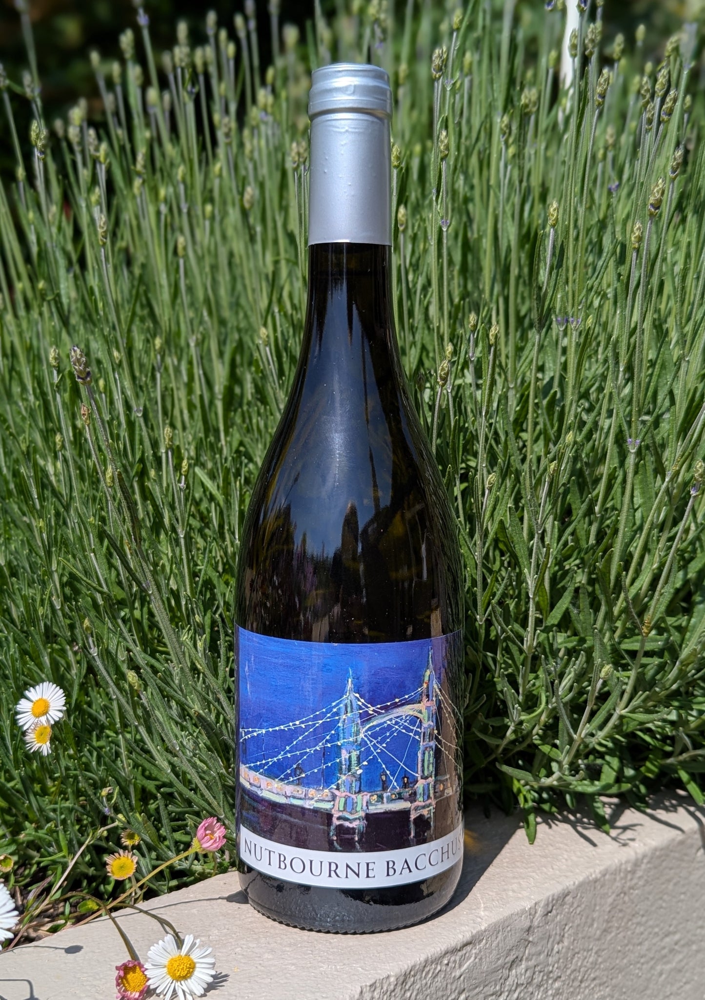 Bottle of Nutbourne Bacchus wine against a natural background with greenery and flowers.