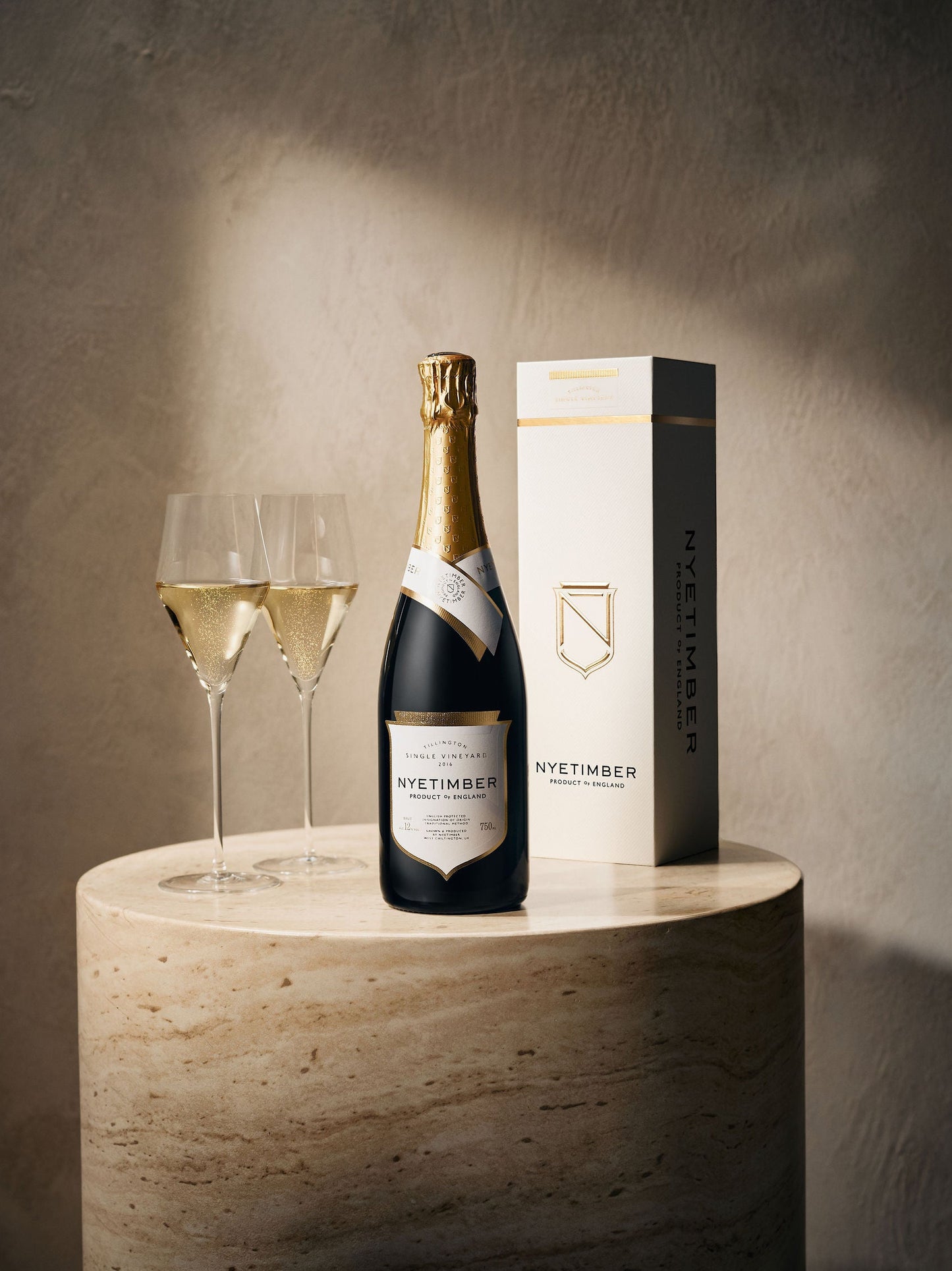 Nyetimber champagne bottle and glasses on a wooden stand with a neutral background. Tillington Single Vineyard.